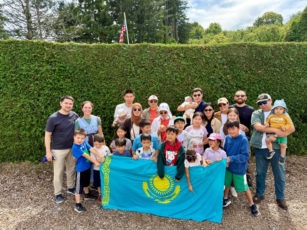 Boston Qazaq School families at apple picking, holding the flag of Kazakhstan.